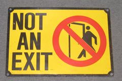 Sign-Not An Exit- metal,yellow/blk red circle 20"x14", stock number S-1512