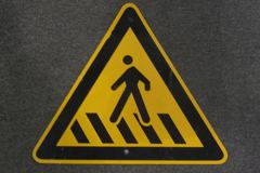 Sign-international symbol for crosswalk, yellow/black, triangular, stock number S-2194